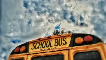 Close-Up High Section Of School Bus Against Clouds