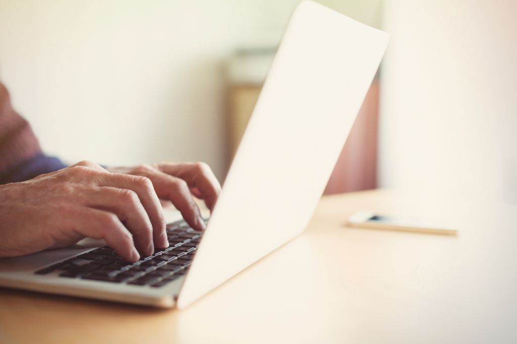 Senior man typing on laptop at table