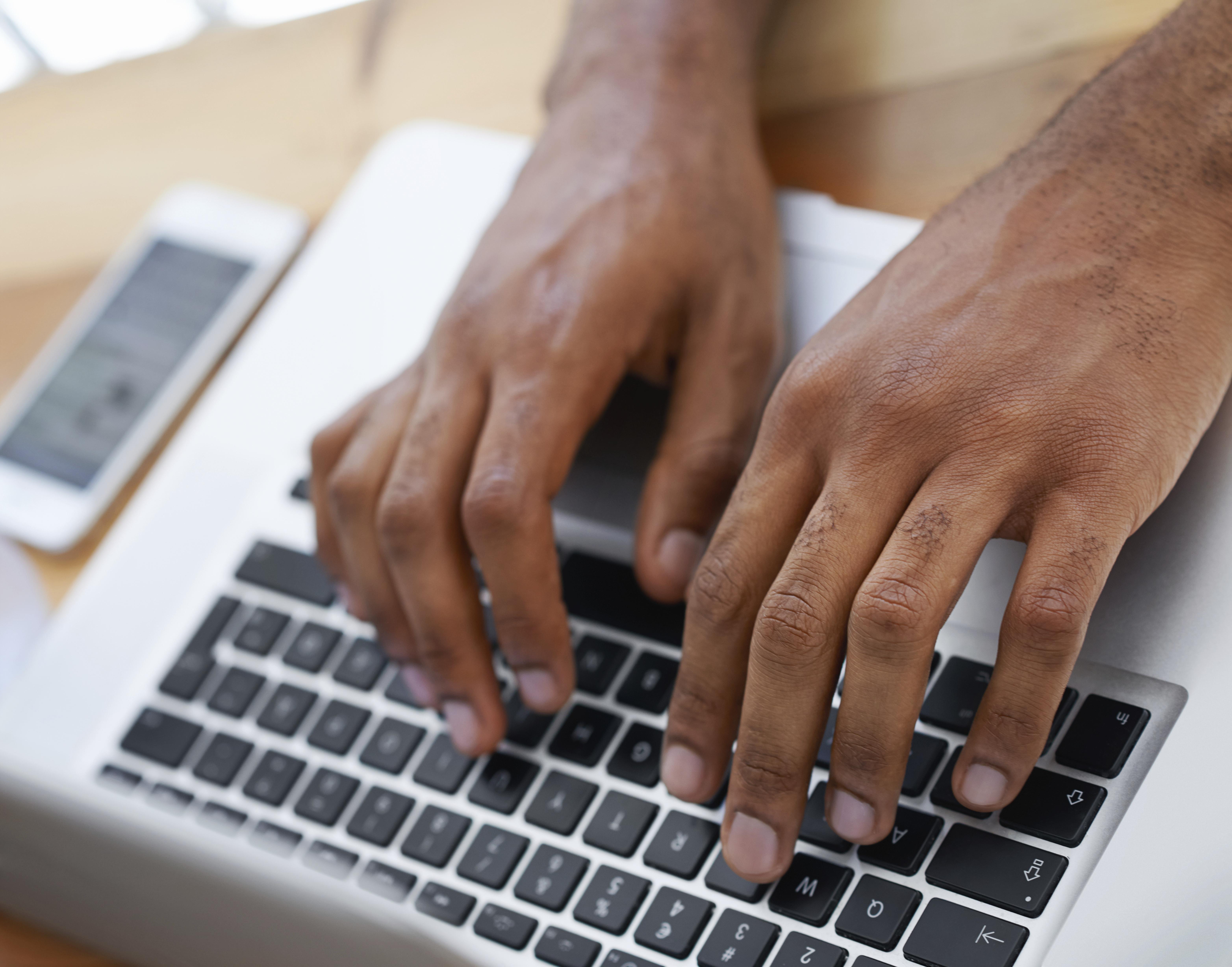 Cropped view of a businessman's hands as he types on his laptop