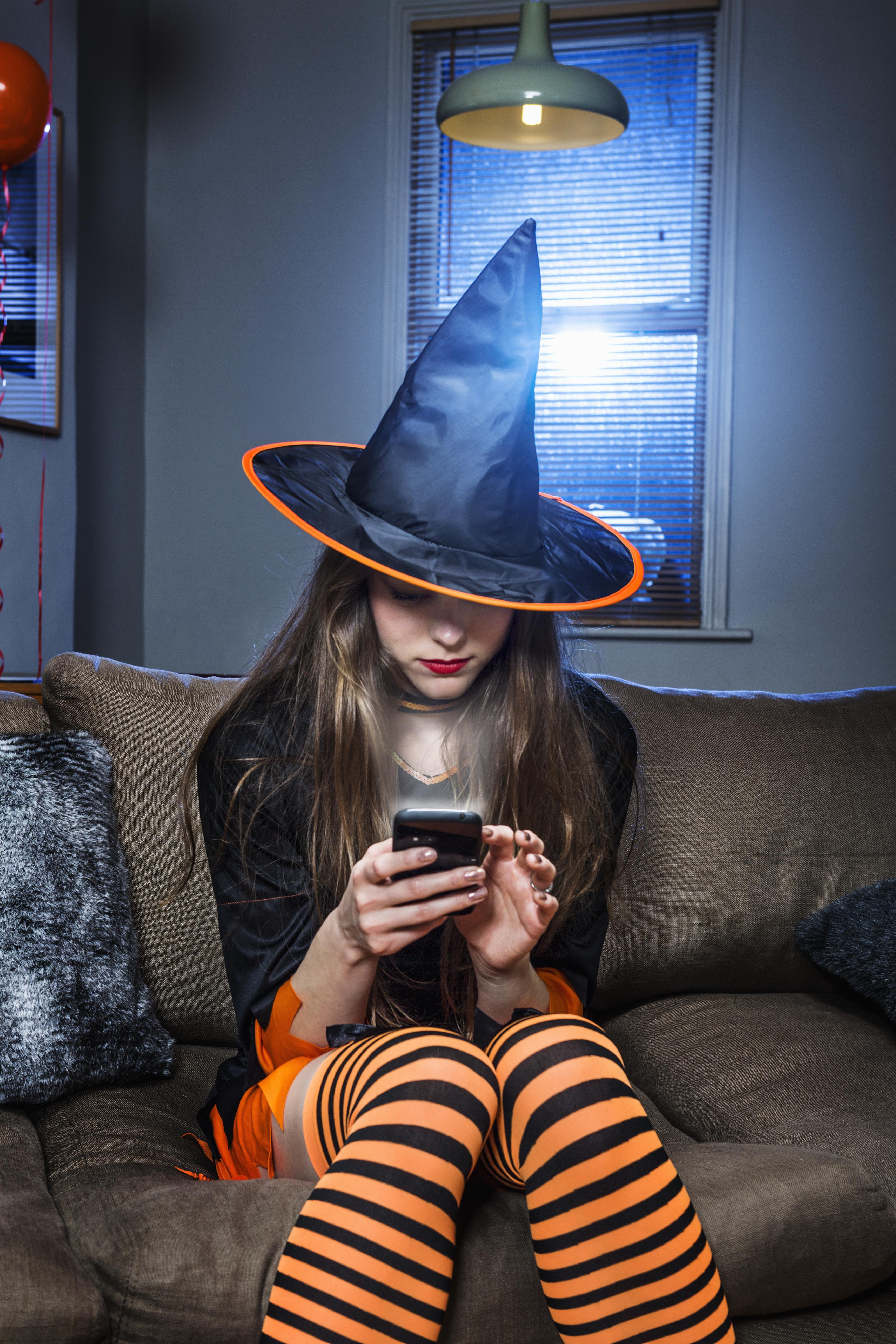halloween witch checking her mobile phone.