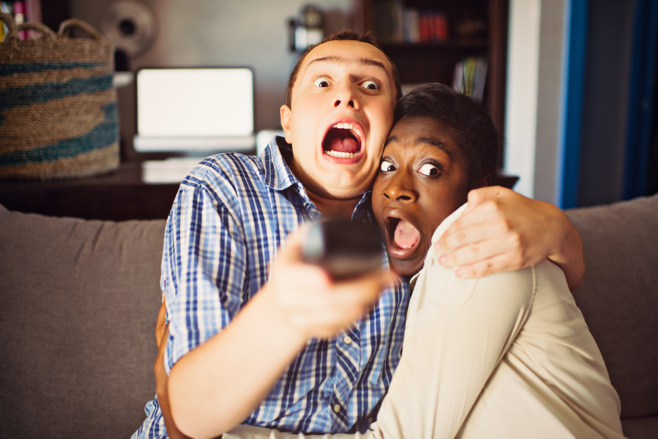 Mixed race teenage couple watching a movie at home