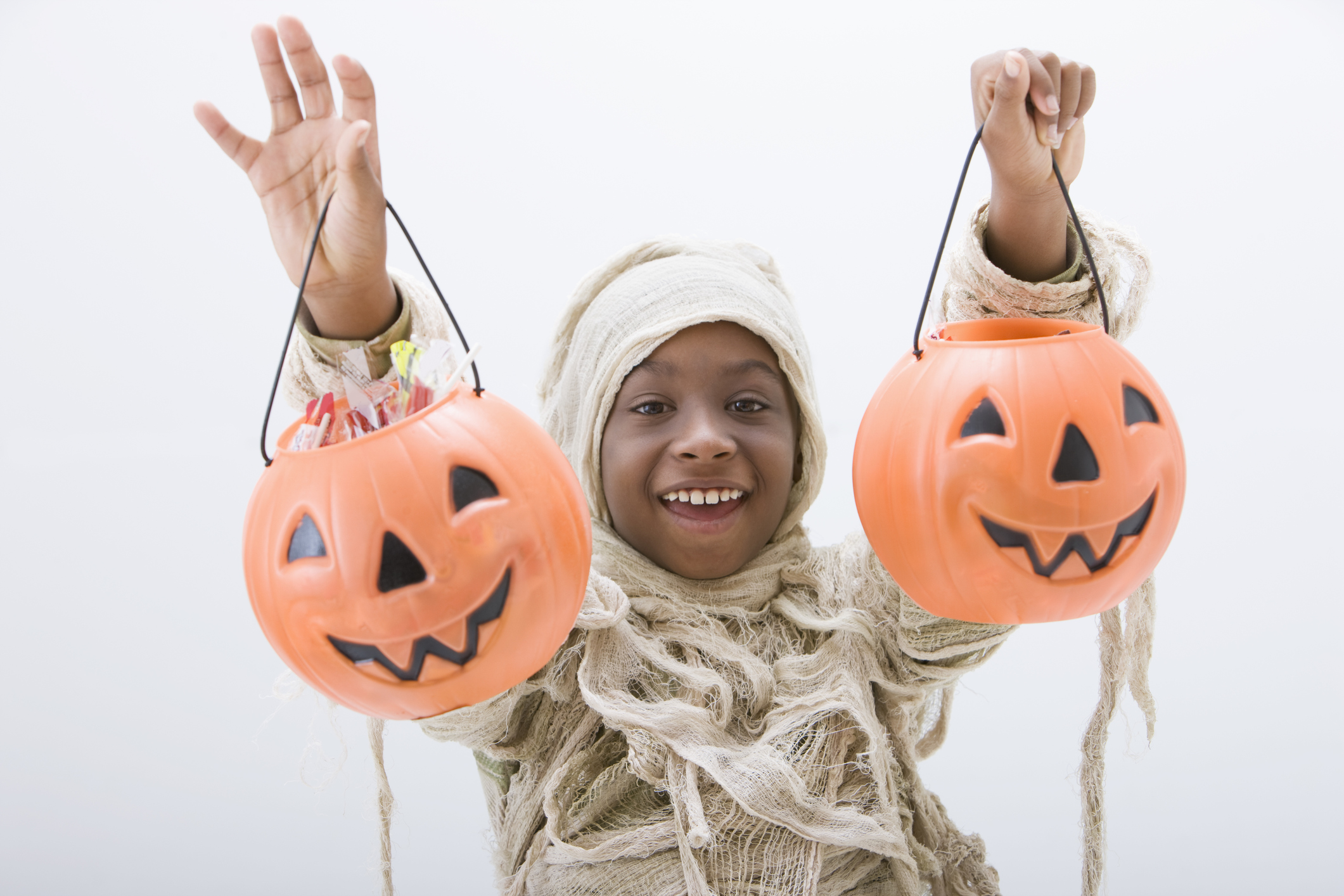 Black boy in mummy costume holding jack o'lanterns