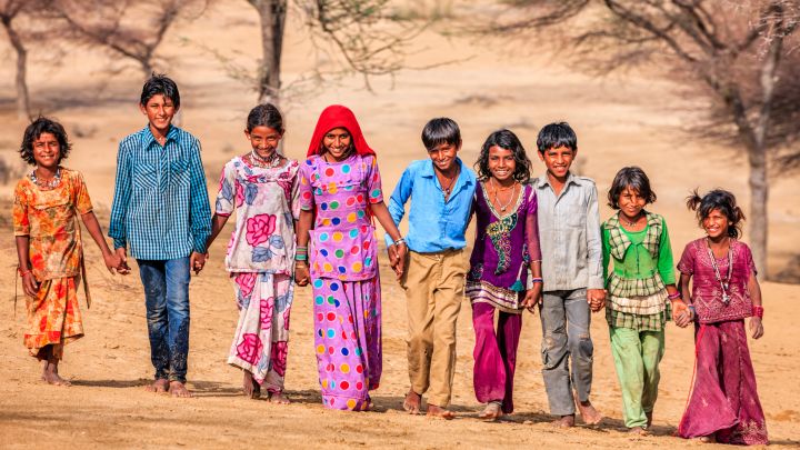 Group of happy Indian children walking across sand dunes, India