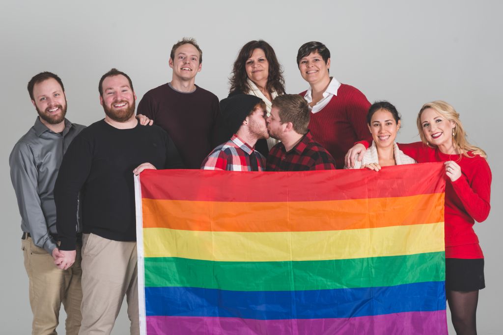 Group of LGBT advocates holding pride flag