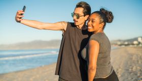 Young couple, Latino man and girl, take selfie on beach