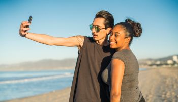 Young couple, Latino man and girl, take selfie on beach