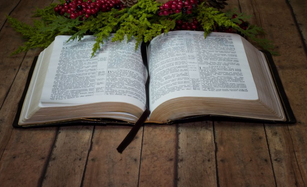 Opened Holy Bible with Christmas Garland on wood plank board