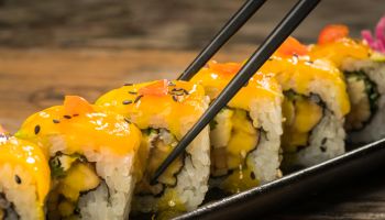 Yellow sushi roll with chopstick on the plate.