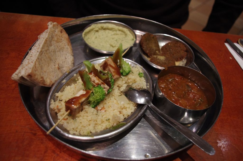 Vegetarian mezze platter with tofu and broccoli skewer with peanut sauce, couscous, pita bread, fava bean dip, falafel, and eggplant curry