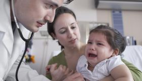 Hispanic male doctor examining crying baby
