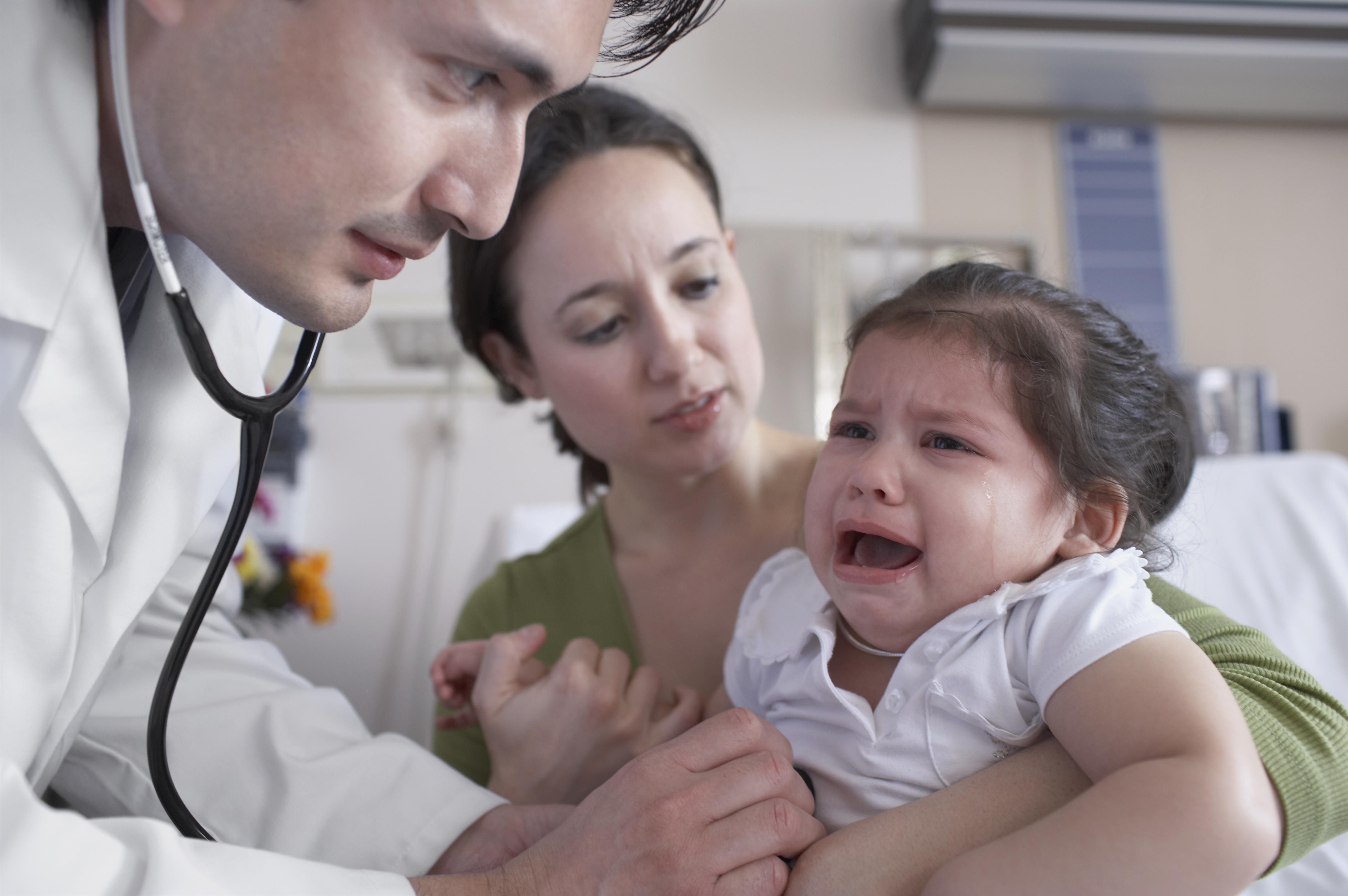 Hispanic male doctor examining crying baby