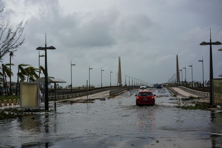 San Juan, PR: Cars cross flooded waters on a bridge.