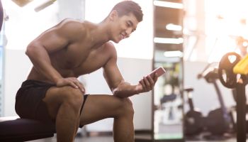 Young man using smart phone in gym