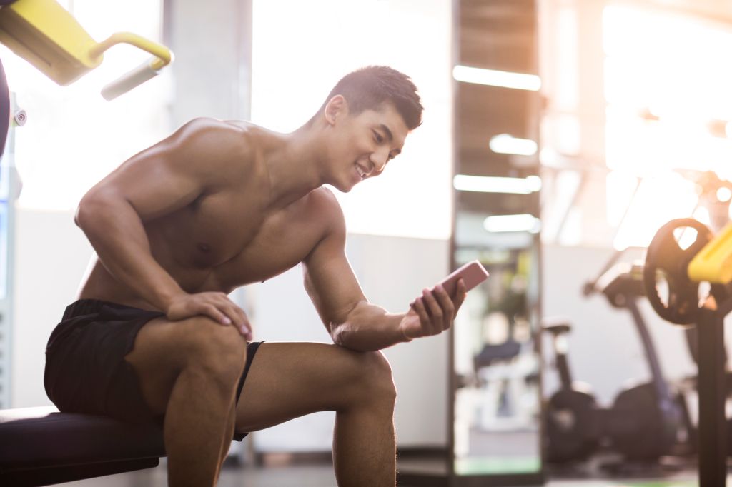 Young man using smart phone in gym