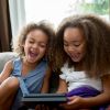 Mixed race girls using digital tablet on sofa
