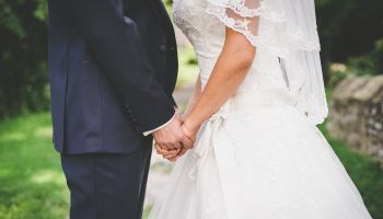 Midsection Of Couple Holding Hands At Wedding