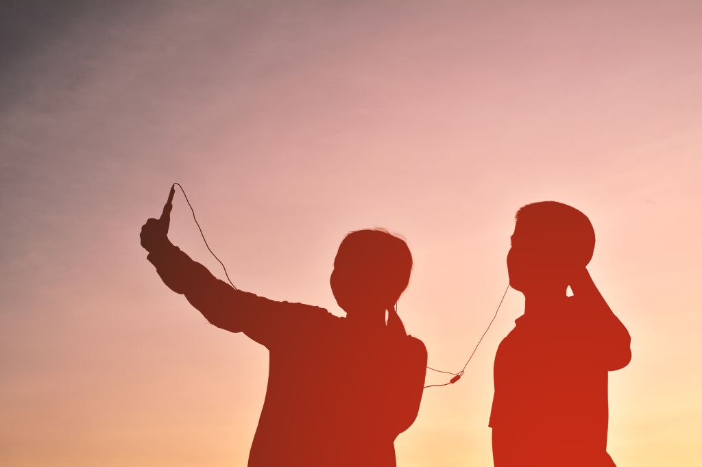 Silhouette Friends Taking Selfie While Listening Music Through Headphones Against Sky During Sunset