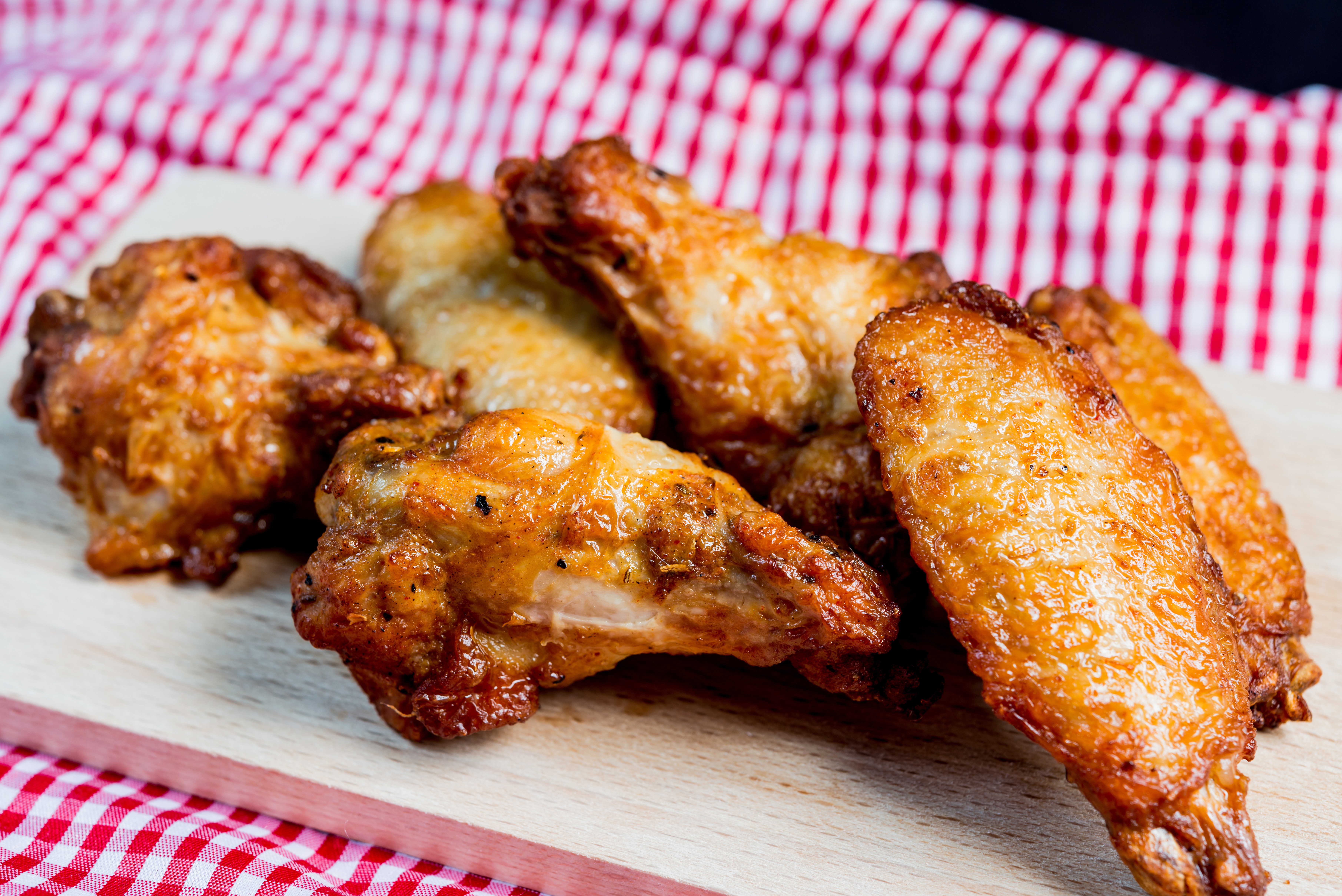 Close-Up Of Chicken Wings On Wooden Board Against Black Background
