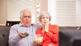 Senior adult couple at home watching television together.