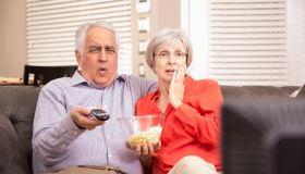 Senior adult couple at home watching television together.