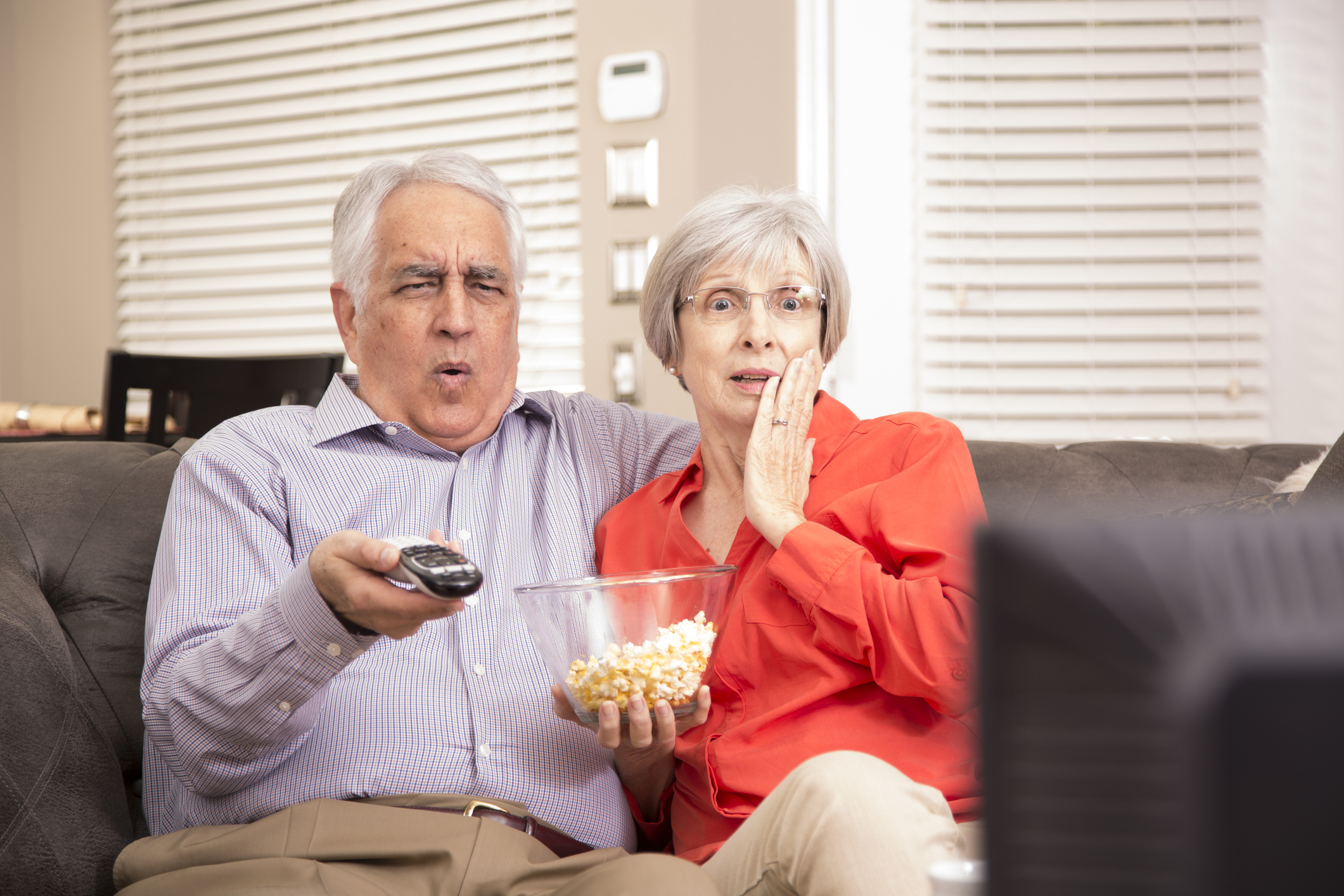 Senior adult couple at home watching television together.