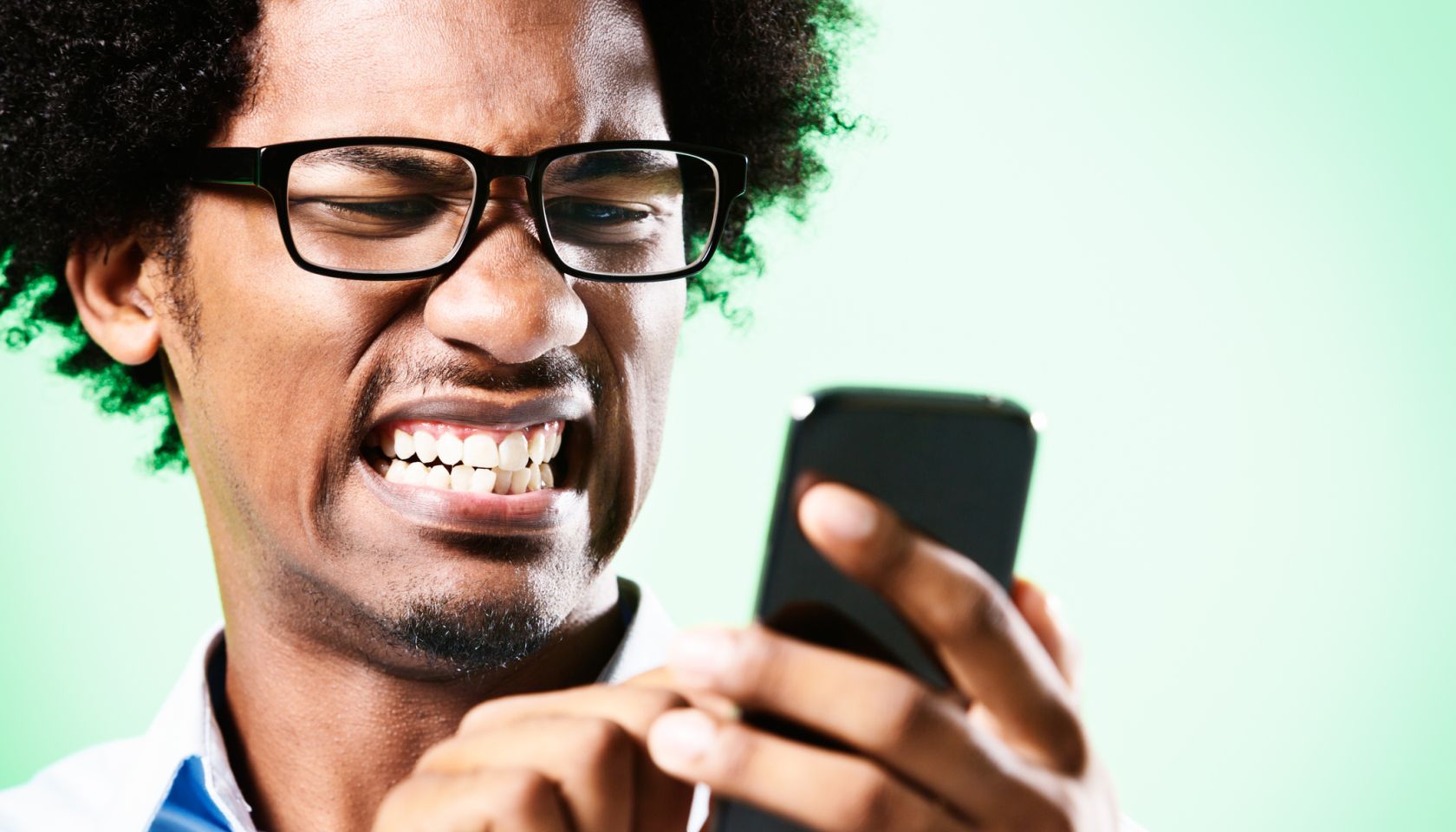 Young afro-haired nerd grimaces at cellphone he holds