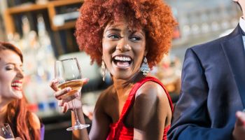 Young black woman in bar drinking, laughing