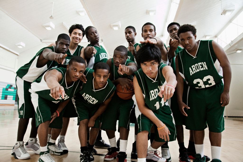 Basketball players pointing at camera in gym