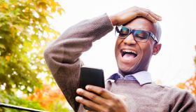 Mature man laughs out loud at story on mobile phone