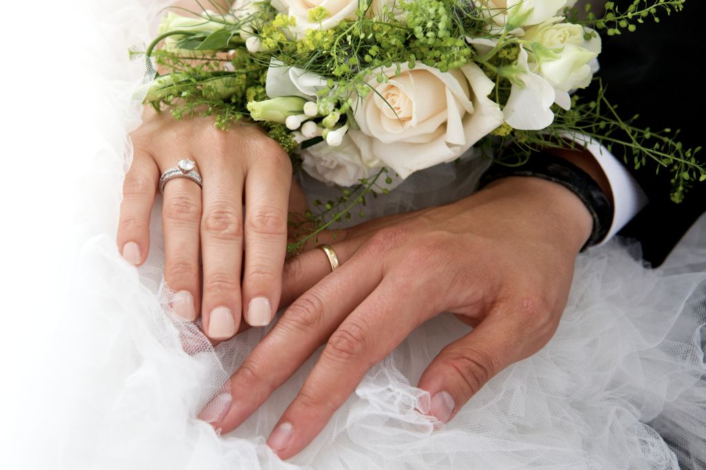Close-Up Of Newlywed Couple Holding Rose Bouquet