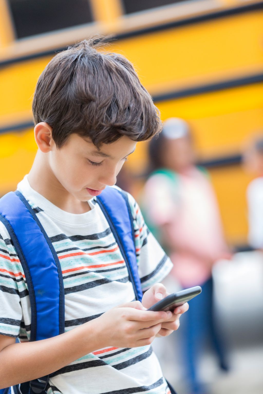 Schoolboy uses smart phone while waiting for bus