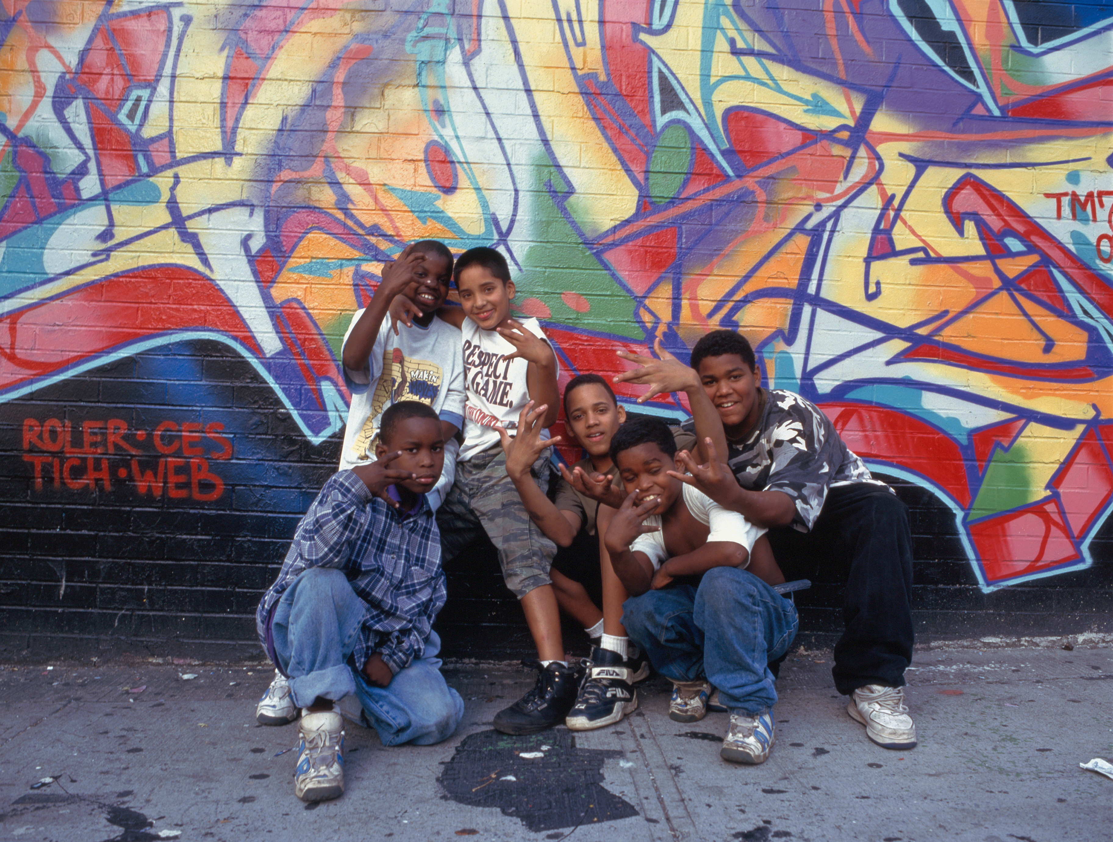 Small group of teenagers in front of graffiti on wall