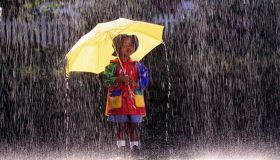Boy (4-6) wearing raincoat, standing under umbrella in rain