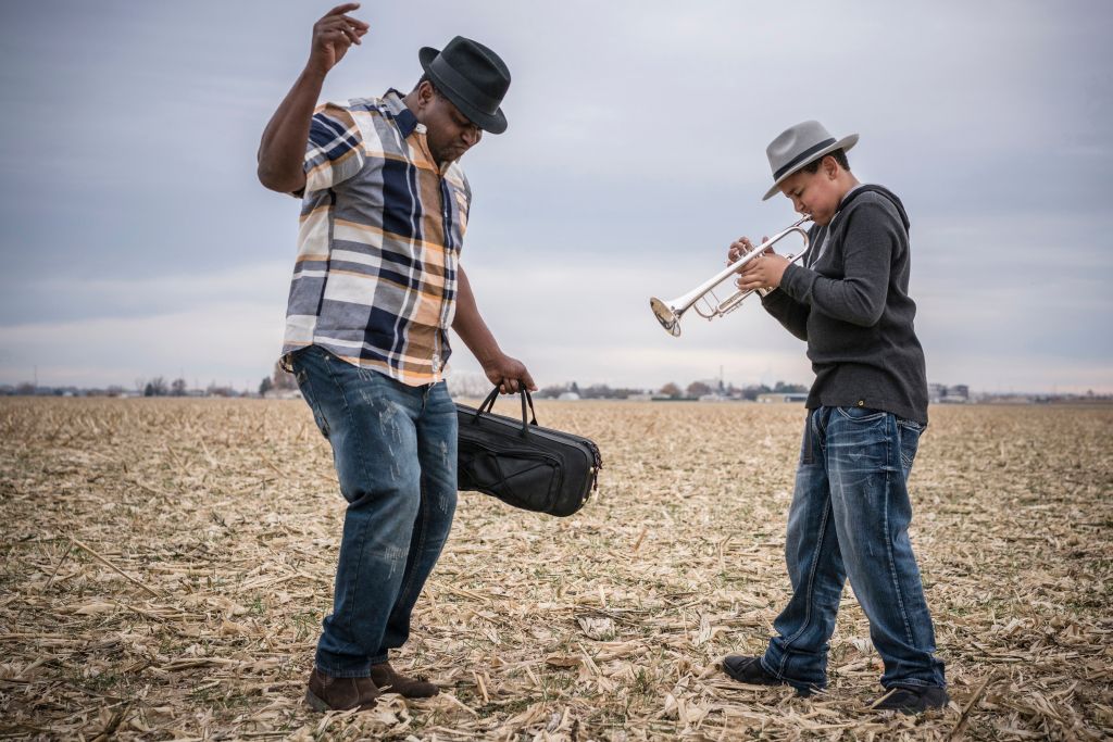 Father dancing to son playing trumpet in field