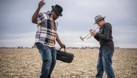 Father dancing to son playing trumpet in field