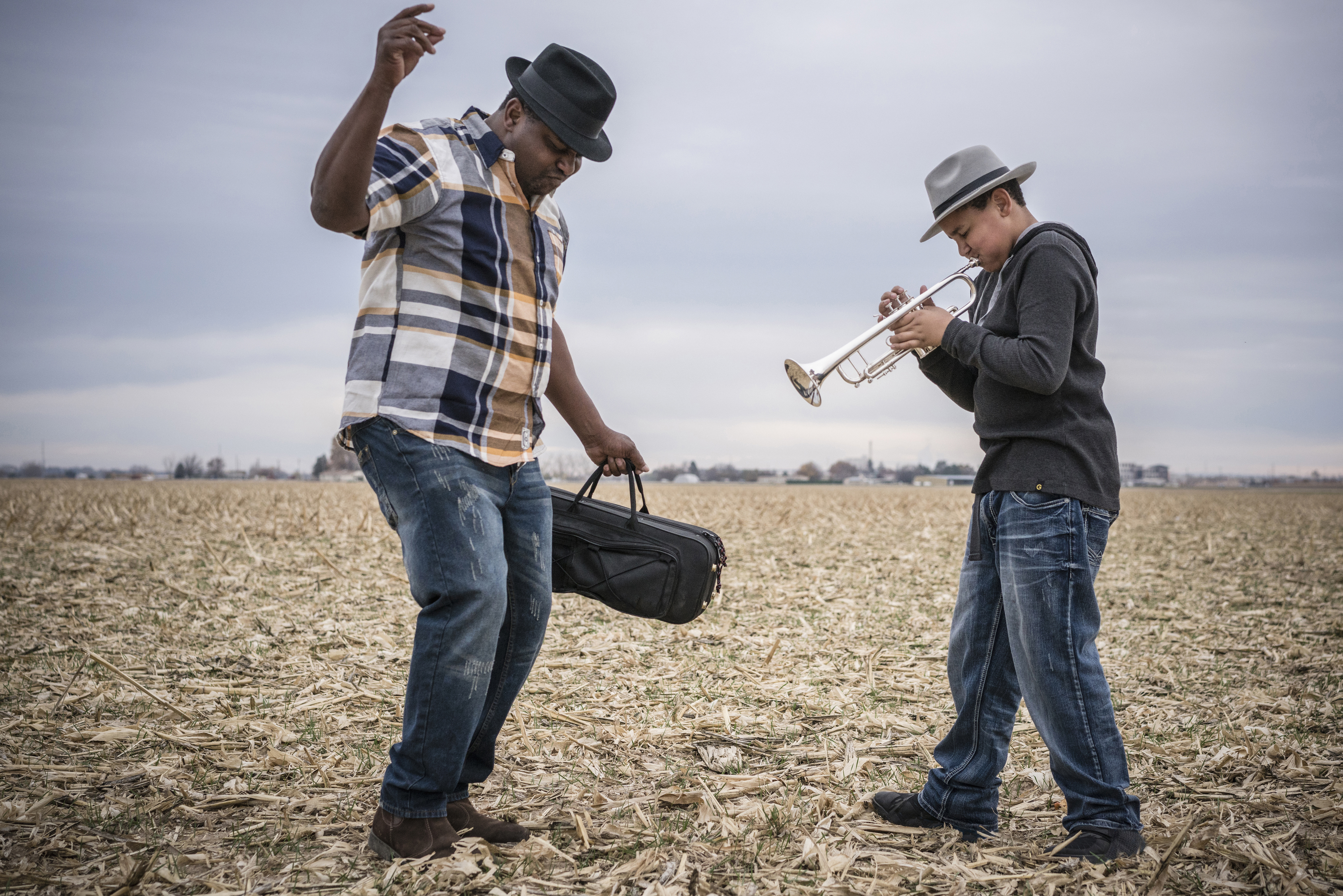 Father dancing to son playing trumpet in field