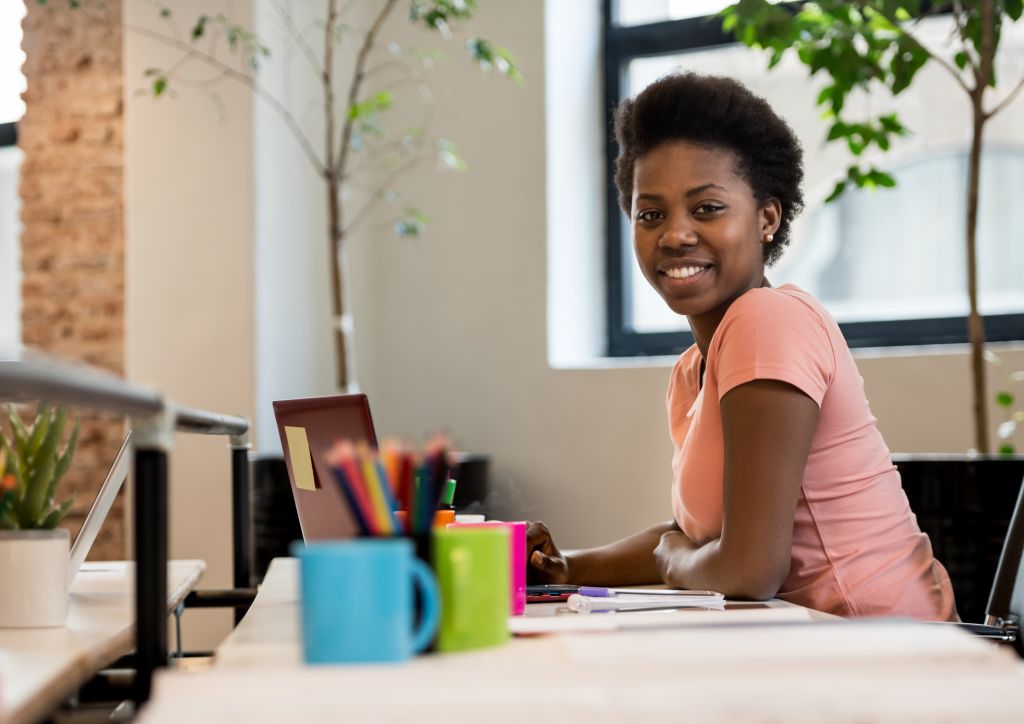 Happy black woman working online at a creative office