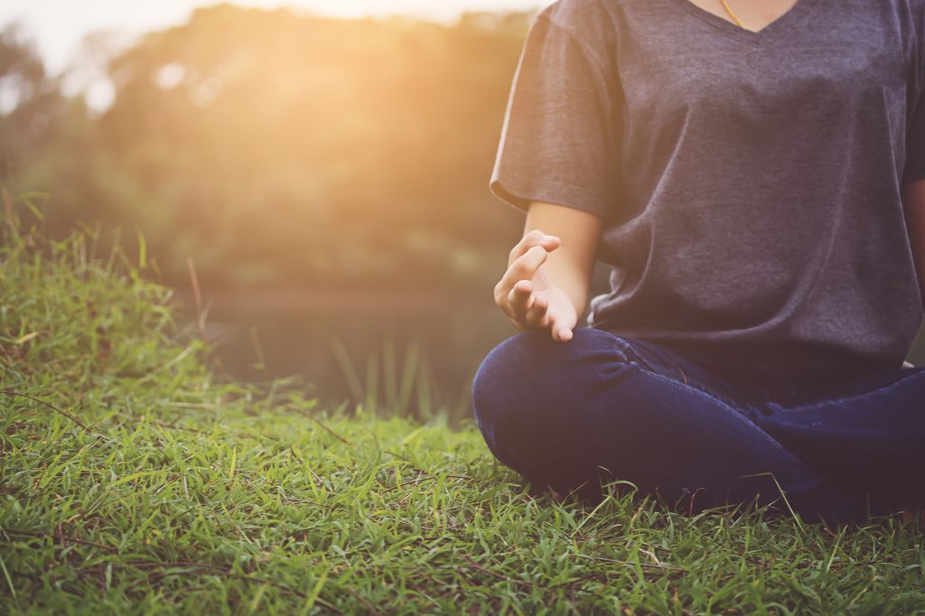 Low Section Of Woman Practicing Yoga While Sitting On Grassy Field