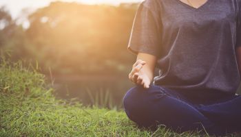 Low Section Of Woman Practicing Yoga While Sitting On Grassy Field