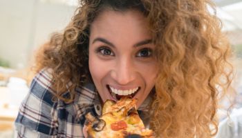 Happy woman eating pizza at a restaurant