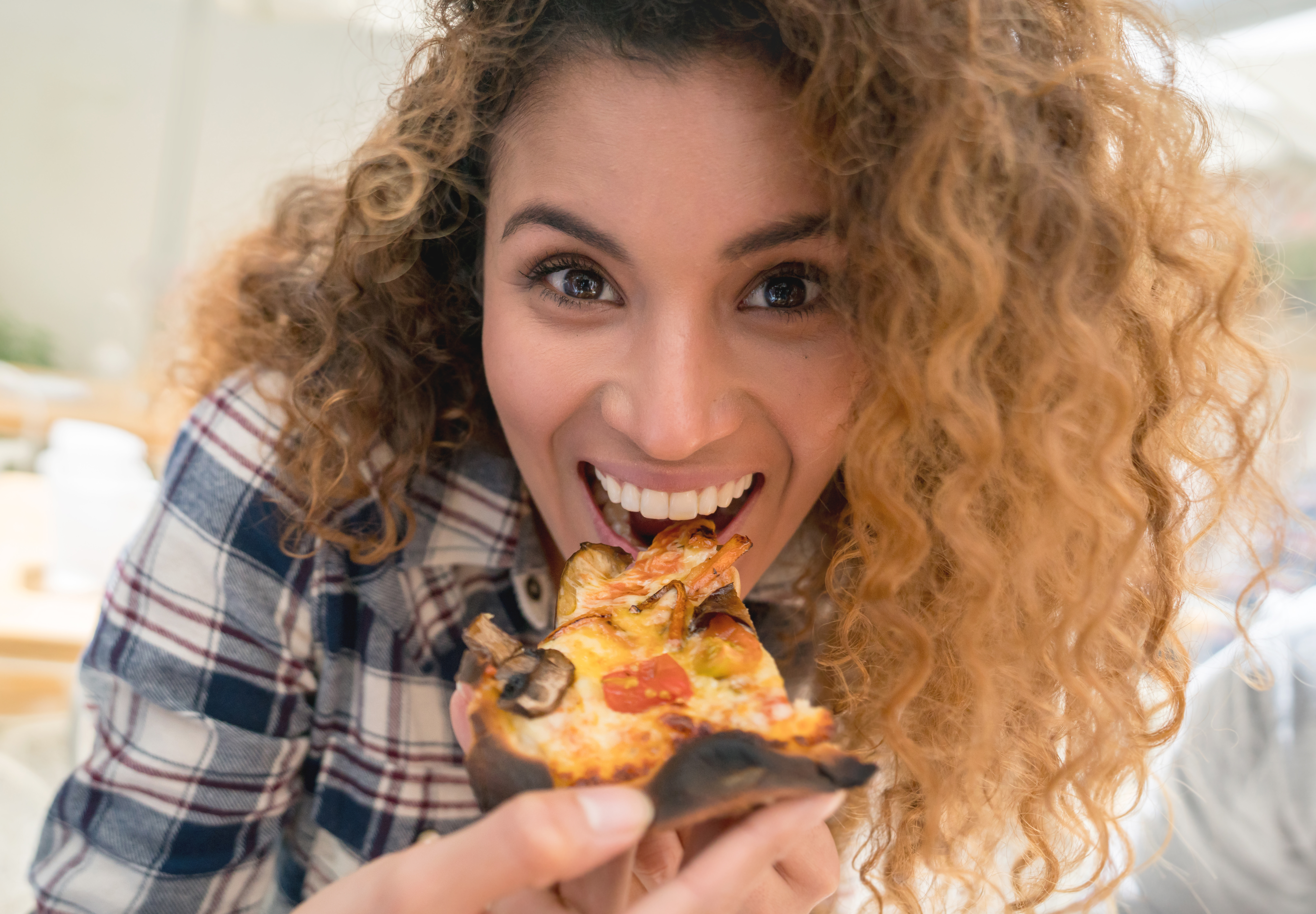 Happy woman eating pizza at a restaurant