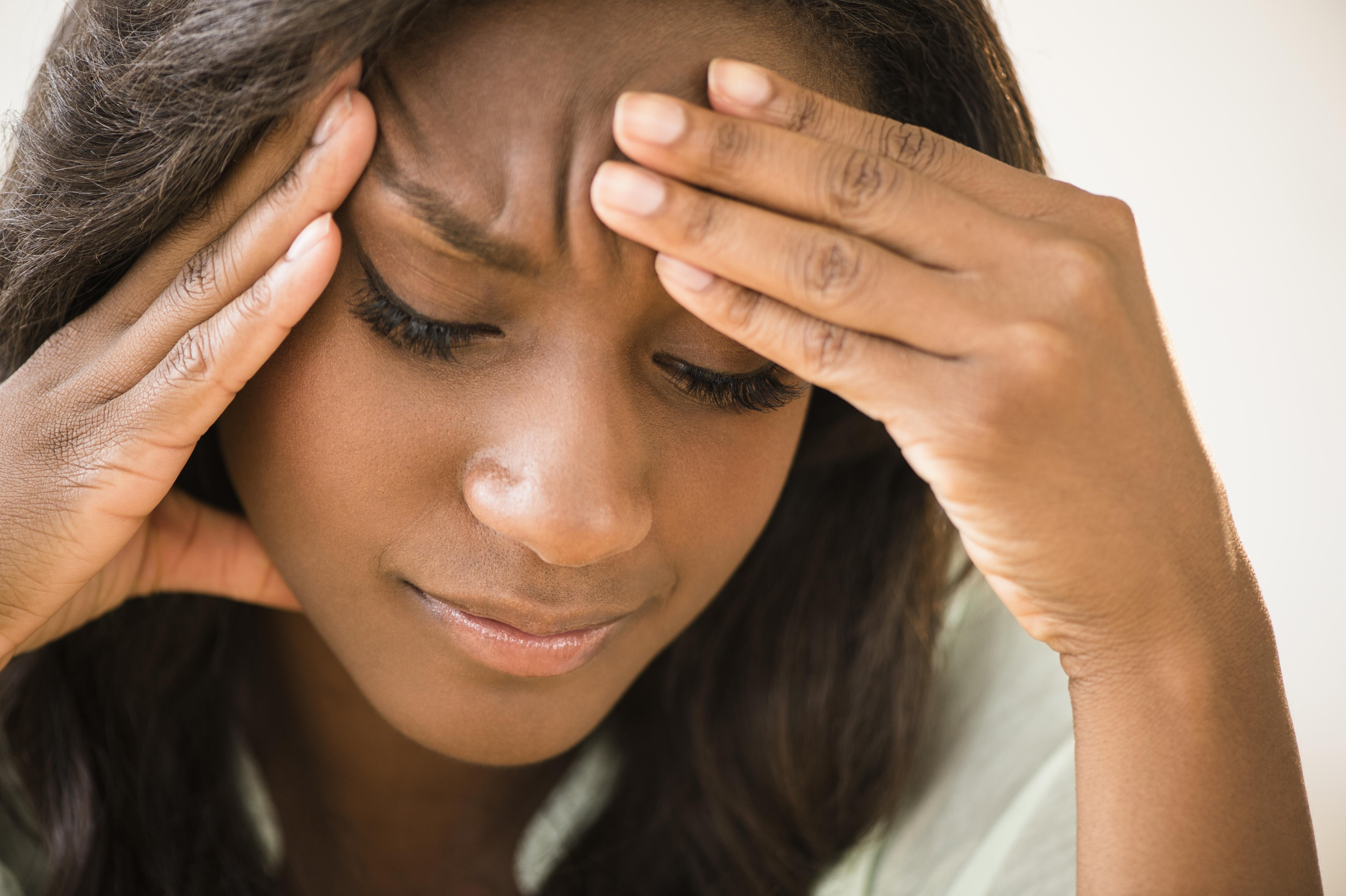 Black woman frowning with head in hands