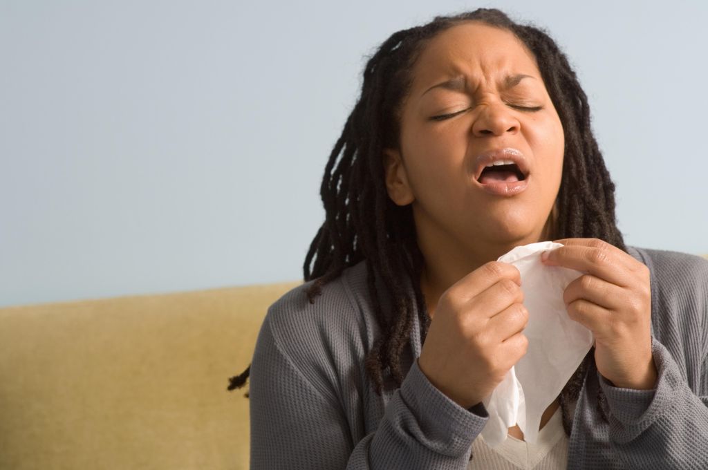 Woman preparing to sneeze into tissue, indoors