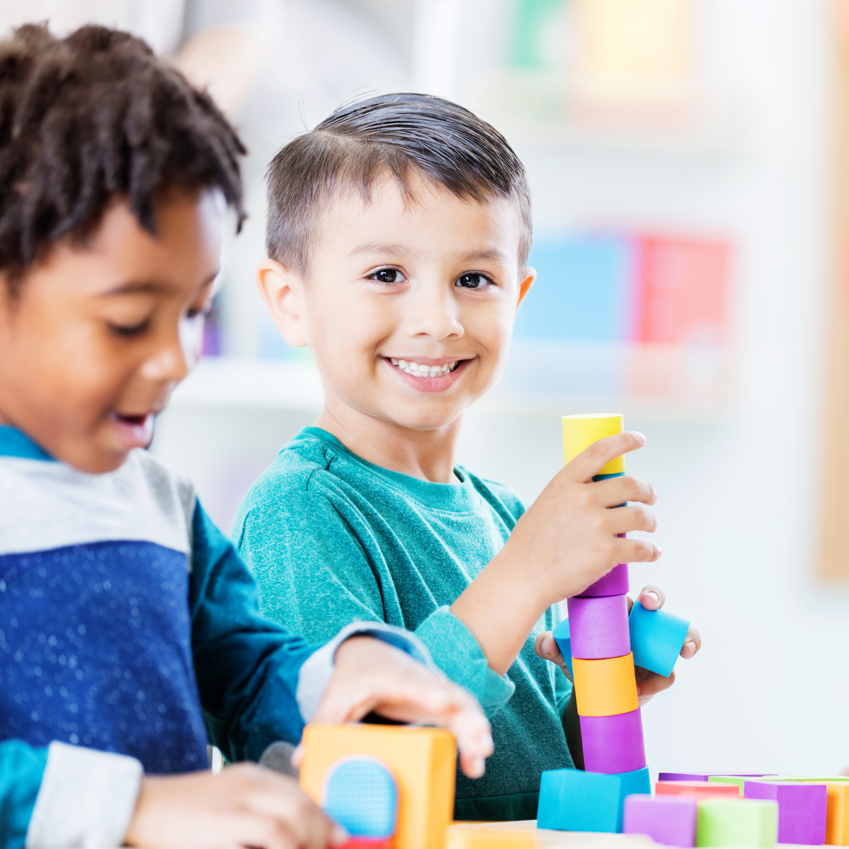 Playful kindergarten student plays with building blocks