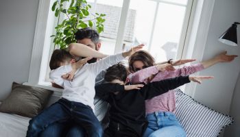 Cheerful family doing dab while sitting on sofa in living room at home