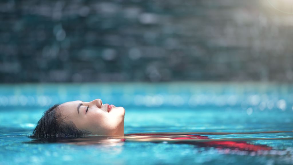 Close up view of an attractive young woman relaxing on a spa's swimming pool on top of roof deck building . Travel, happiness emotion, summer holiday concept .