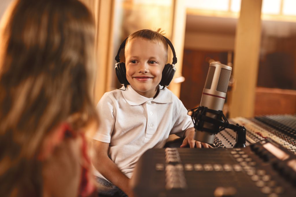 Happy little commentator having a guest in a radio station during live broadcast.