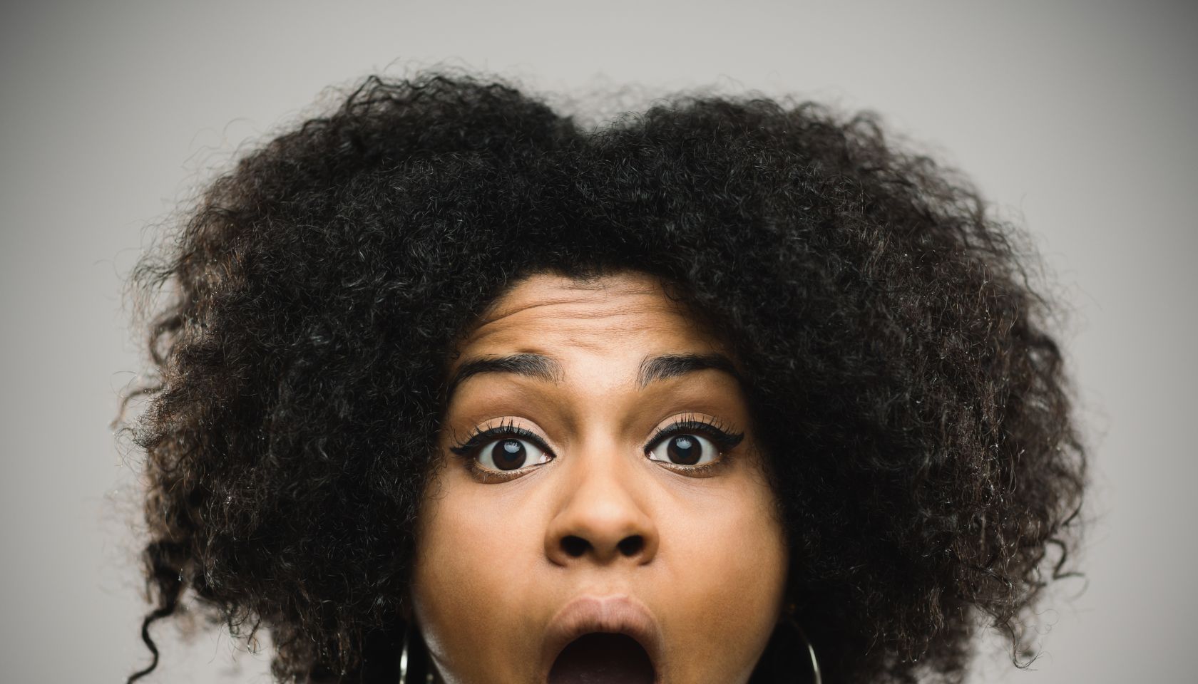 Close-up portrait of a shocked real young afro american woman