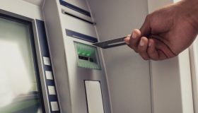 Close up of unrecognizable person with credit card on ATM.