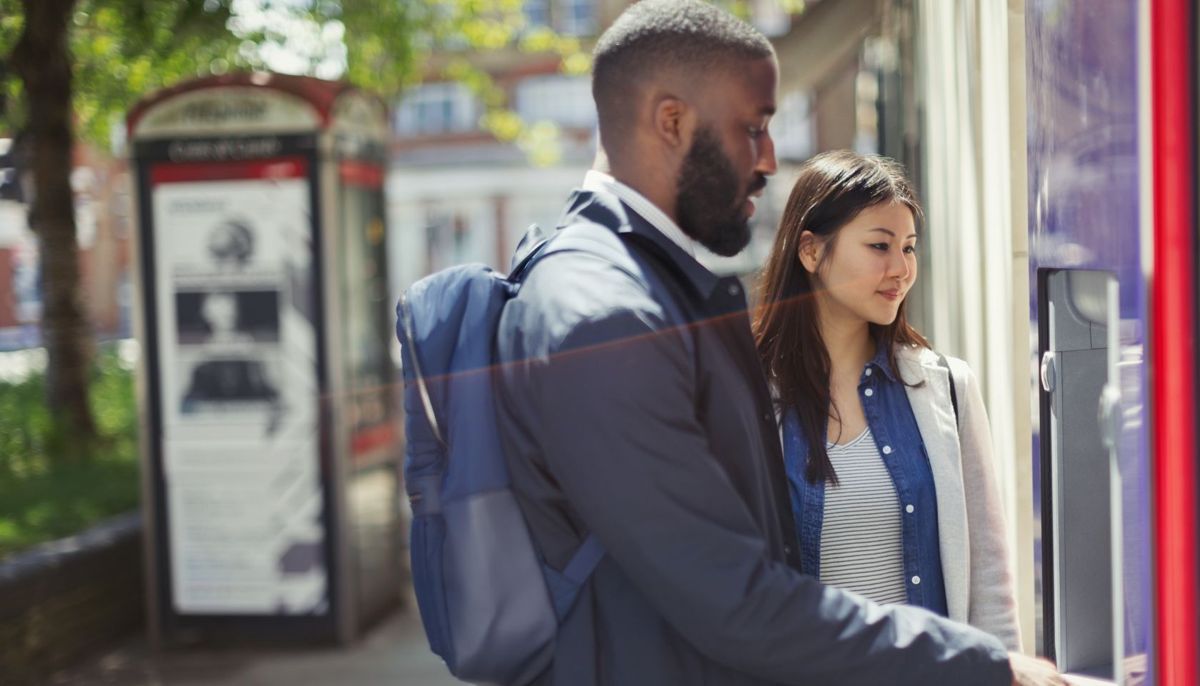 Young couple using urban ATM
